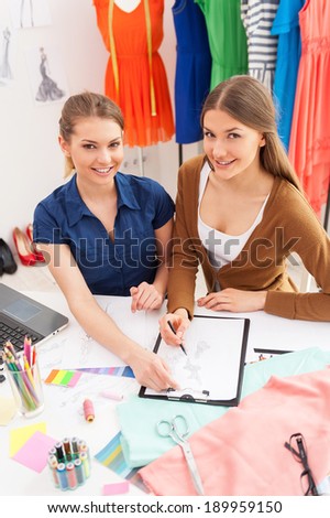 Fashion designers at work. Top view of two beautiful female designers discussing something while sitting at the working place