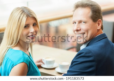 Drinking coffee together. Beautiful mature couple drinking coffee together and looking at camera while sitting in coffee shop