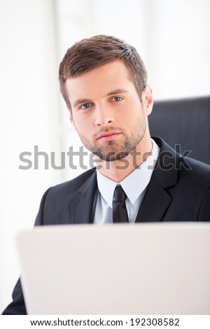 Confident businessman. Confident young man in formal wear looking at camera while sitting at his working place