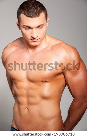 Always in good shape. Handsome young muscular man posing while standing against grey background