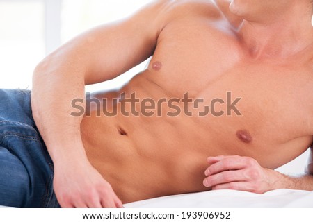Perfect body. Close-up of muscular man lying in bed
