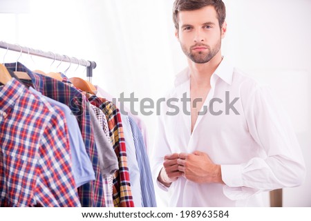 Stylish and elegance. Handsome young man dressing up white shirt and looking at camera