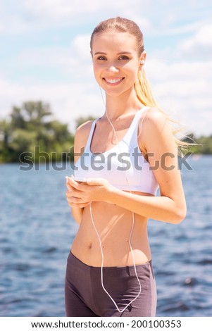 Sporty woman. Beautiful young woman in sports wear standing outdoors and smiling