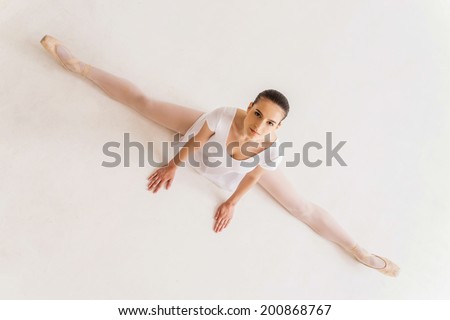 It takes discipline to be the best. Top view of young ballerina in white tutu doing splits