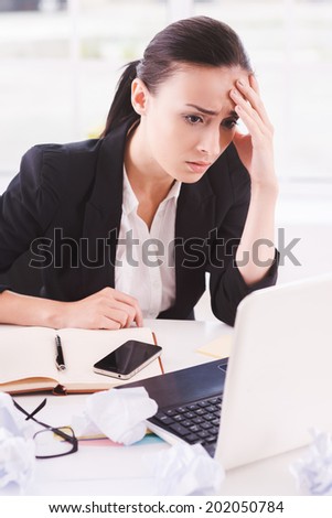 Busy office life. Frustrated young woman in formalwear looking at computer while sitting at her working place