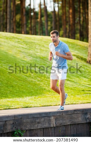 Man on his everyday jog. Full length of confident young man running along quayside