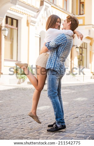 Happy loving couple. Full length of beautiful young loving couple hugging and looking at each other while standing outdoors