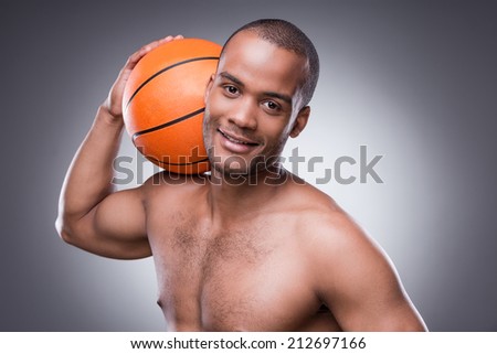 Ready for a game. Young shirtless African man holding basketball ball and looking at camera while standing against grey background