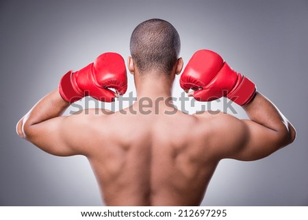 Simply the best. Rear view of shirtless African man in boxing gloves standing against grey background