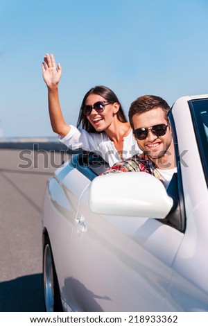 Enjoying their road trip. Happy young couple enjoying road trip in their white convertible