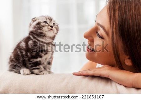 You are my little friend! Beautiful young woman looking at her little kitten and smiling