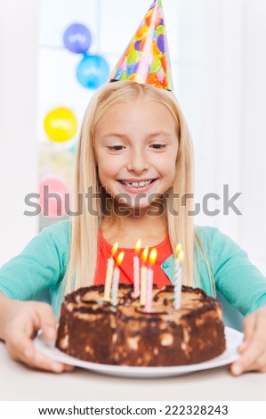 Happy birthday to me! Happy little girl looking at the birthday cake and smiling