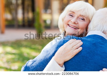 He makes me happy. Happy senior woman embracing her husband and smiling while both standing outdoors