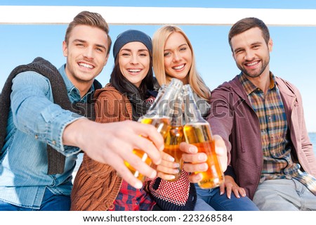 Cheers! Group of young happy people cheering with beer and smiling while bonding to each other