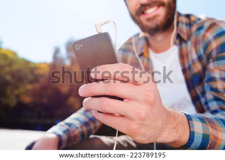 Enjoying the rhythm of his life. Close-up of handsome young bearded man smiling while listening to music