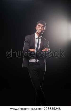 Being successful suiting him. Handsome young Afro-American man keeping arms and legs crossed