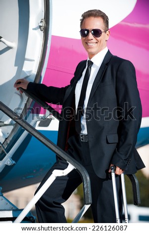 Ready to new business trip. Confident mature businessman moving up by airplane ladder to the entrance