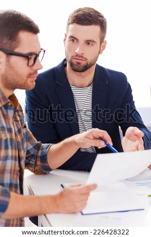 Discussing project. Two confident business people in smart casual wear sitting together at the table and discussing something