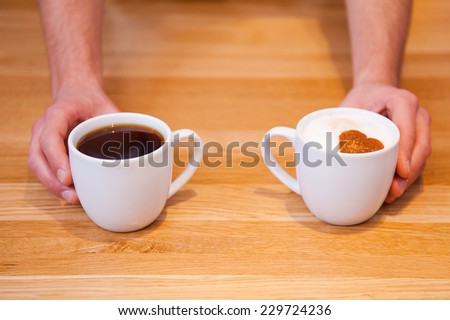 Fresh coffee with love. Close-up top view of male barista serving two cups of fresh coffee for you