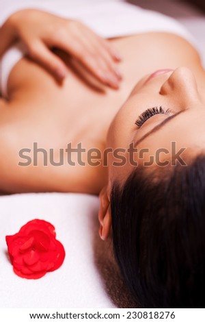 Total relaxation. Cropped image of beautiful young woman wrapped in towel lying on massage table and keeping eyes close