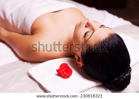 Blissful moments. Top view of beautiful young woman wrapped in towel lying on massage table and keeping eyes close