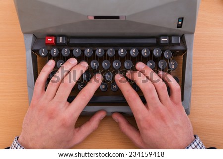 Working at the typewriter. Top view of man typing something on typewriter