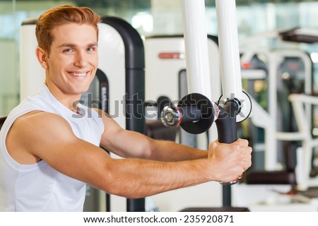 It is very important to stay fit. Handsome young man working out in gym and smiling