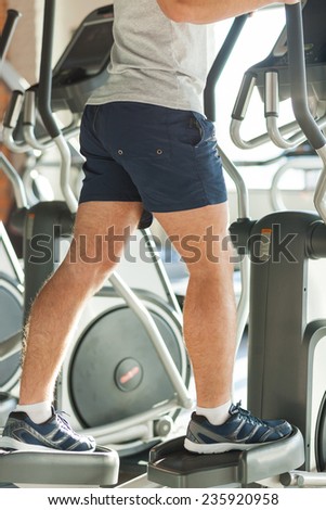 Exercising on step machine. Cropped image of man doing cardio exercise on step machine