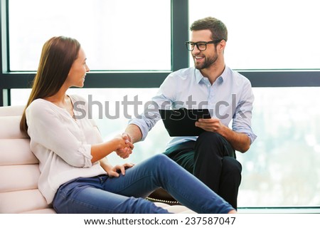 Thank you doctor! Cheerful male psychiatrist shaking hand to beautiful young woman sitting close to him