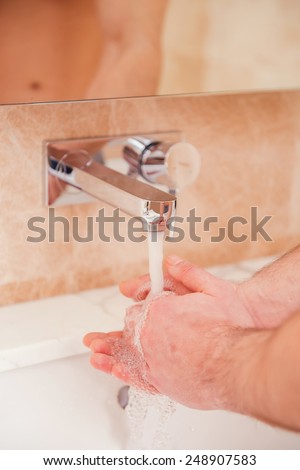 Keeping hands clean. Close-up of man washing hands in bathroom