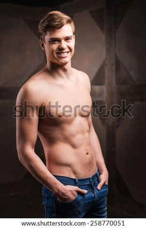 Strength and masculinity. Handsome young muscular man posing while standing against metal background
