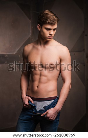 Feeling the perfetion. Handsome young muscular man posing while standing against metal background