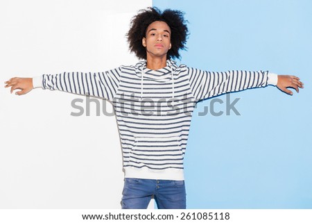 Confident and handsome. Handsome young African man stretching out his arms while standing against colorful background