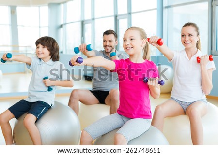 Exercising together is fun. Happy sporty family exercising in sports club together