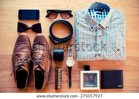 The most important things. Top view of clothing and diverse personal accessory laying on the wooden grain