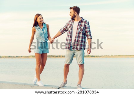 Walking through life hand in hand. Loving young couple holding hands and smiling while walking outdoors