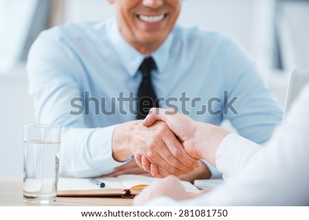 Sealing a deal. Close-up of two business people shaking hands while sitting at the working place