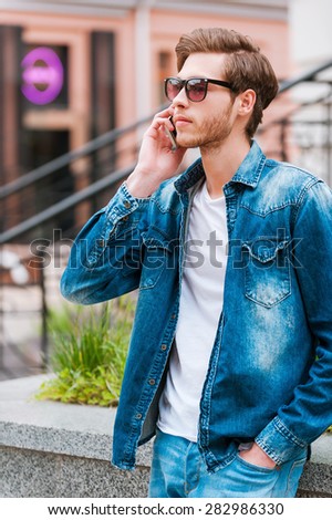 On the wave of city life. Confident young man talking on the mobile phone while standing outdoors