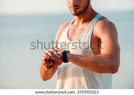 It was a great workout. Cropped image of young muscular man checking time on his watches while standing outdoors