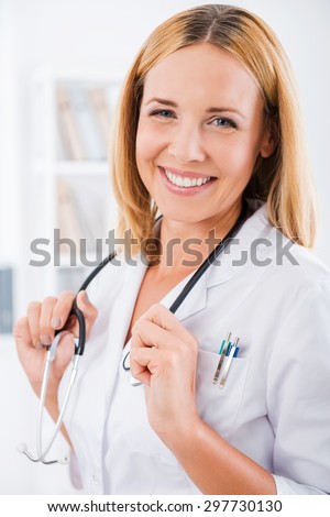Experienced female doctor. Happy female doctor in white uniform looking at camera and smiling