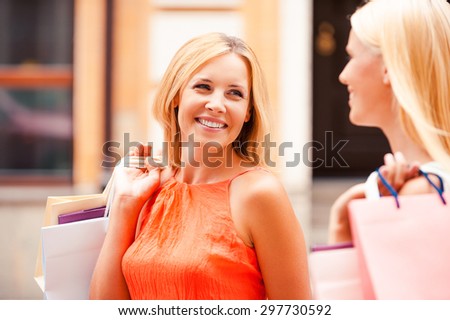 Spending time with daughter. Beautiful mature woman and her daughter carrying shopping bags and looking at each other while walking along the street