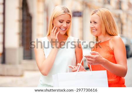 I want you to have it. Happy mature woman holding shopping bag while her daughter looking inside of it and smiling