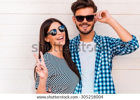 Peace out! Happy young loving couple looking at camera and smiling while standing outdoors