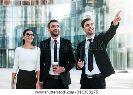 Bringing new business ideas in to life. Three joyful young business people looking away and smiling while standing outdoors