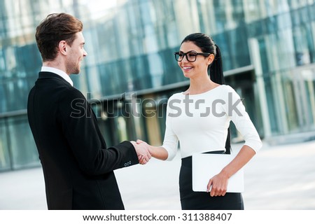 Welcome on board! Two smiling young business people shaking hands while standing outdoors