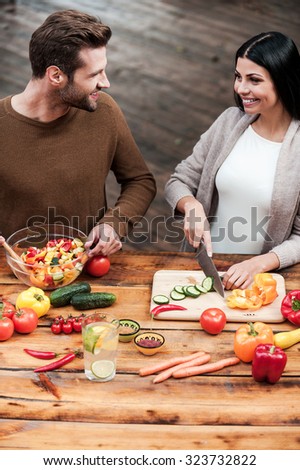 They love cooking together. Top view of beautiful young couple preparing food together and smiling