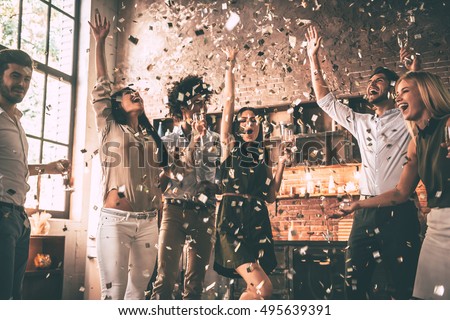 Confetti fun. Group of happy young people throwing confetti and jumping while enjoying home party on the kitchen  Foto d'archivio © 