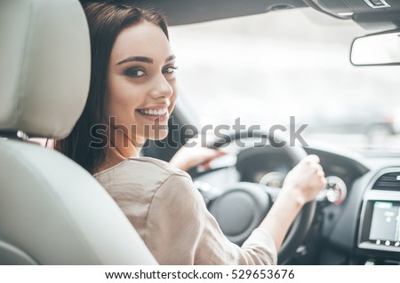 Confident and beautiful. Rear view of attractive young woman in casual wear looking over her shoulder while driving a car  Foto stock © 