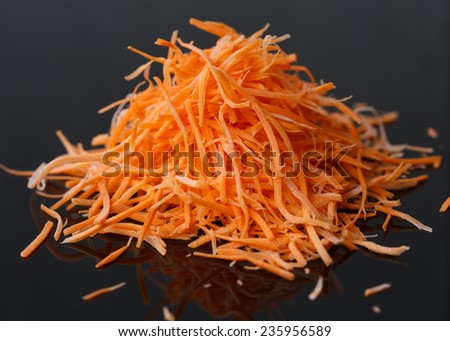 Fresh grated carrot on a black background