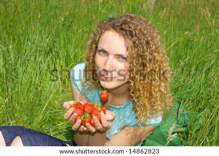 beautiful girl with strawberry in hands and in a mouth